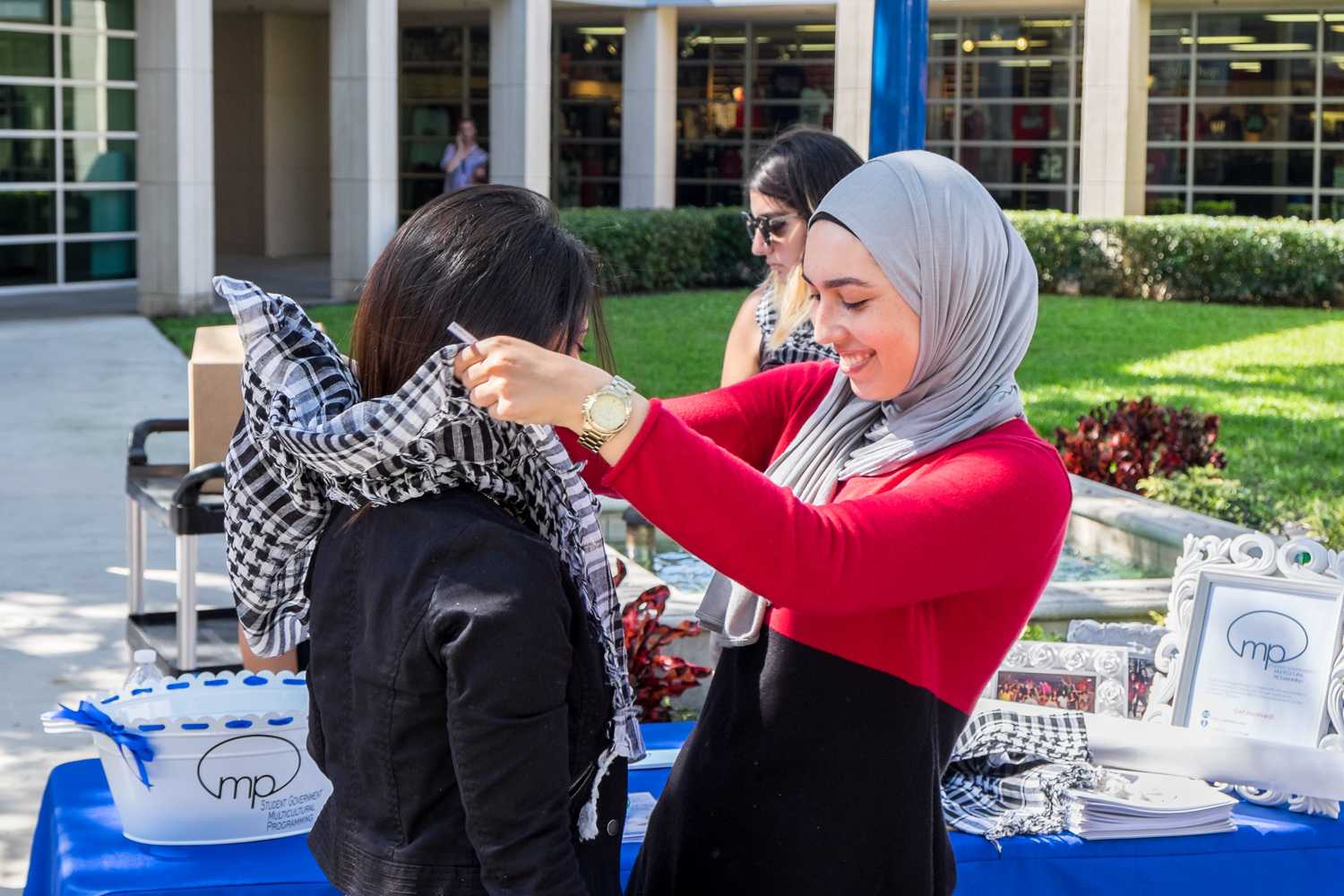SJP member showing a student on how to wear a keffiyeh.  [ Mohammed F Emran | Web Editor ]