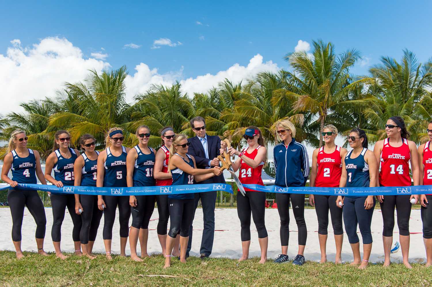 FAU sand volleyball captains Natalie Fraley (12) and Mandy McIntosh (24) are joined by FAU President John Kelly to cut the ribbon to officially open the new sand volleyball courts.