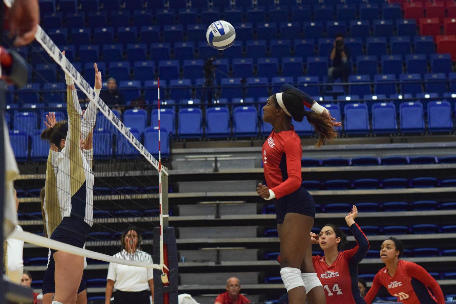 Senior middle blocker Brittany Brown spikes the ball past two Eagles defenders during the first set of their match during the FAU Invitational tournament. Ryan Lynch | Sports Editor 