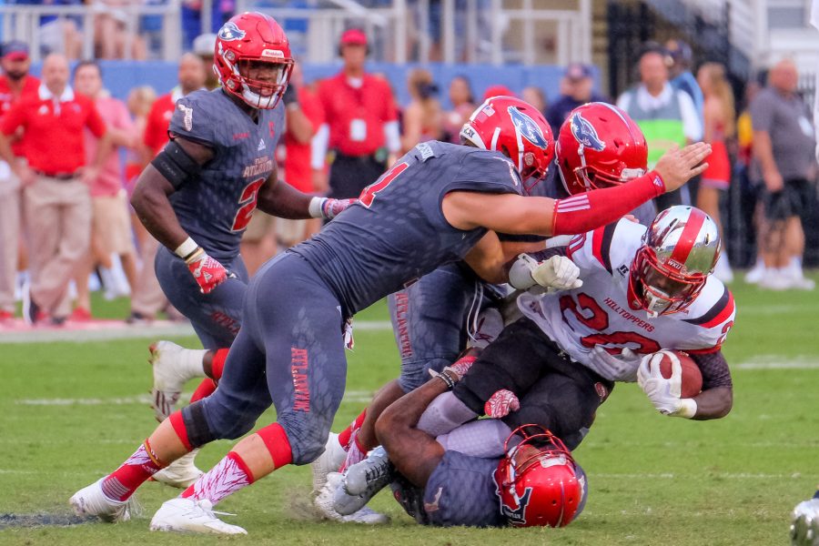 A trio of FAU defenders tackles Hilltoppers running back Anthony Wales(20). Mohammed F Emran | Staff Photographer