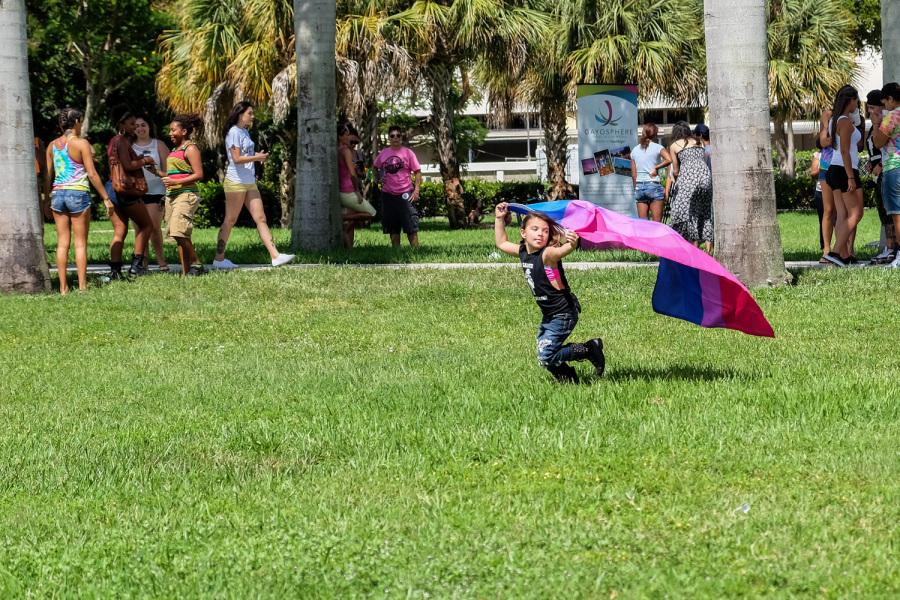 Jaelyn Benson running in the housing lawn with a flag during Pride Fest [Mohammed F Emran | Web Editor]