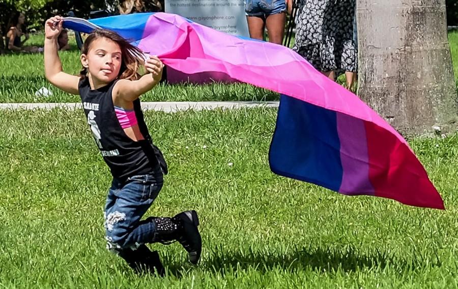Jaelyn Benson running in the housing lawn with a flag during Pride Fest Mohammed F Emran | Staff Photographer
