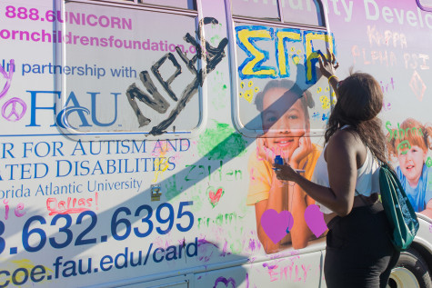 A runner fingerpaints "Sigma Gamma Rho" on a bus. Photo by Max Jackson