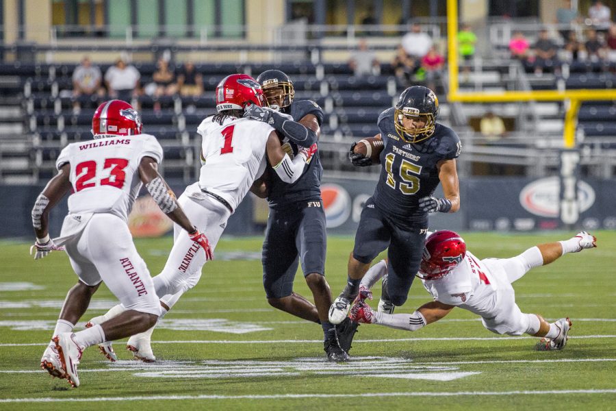 FIU redshirt freshman wide receiver Austin Maloney (15) slips through the hands of FAU redshirt sophomore defensive back Jake Stoshak. Maloney gained 55 yards for the Panthers against FAU Saturday night. Brandon Harrington | Staff Photographer