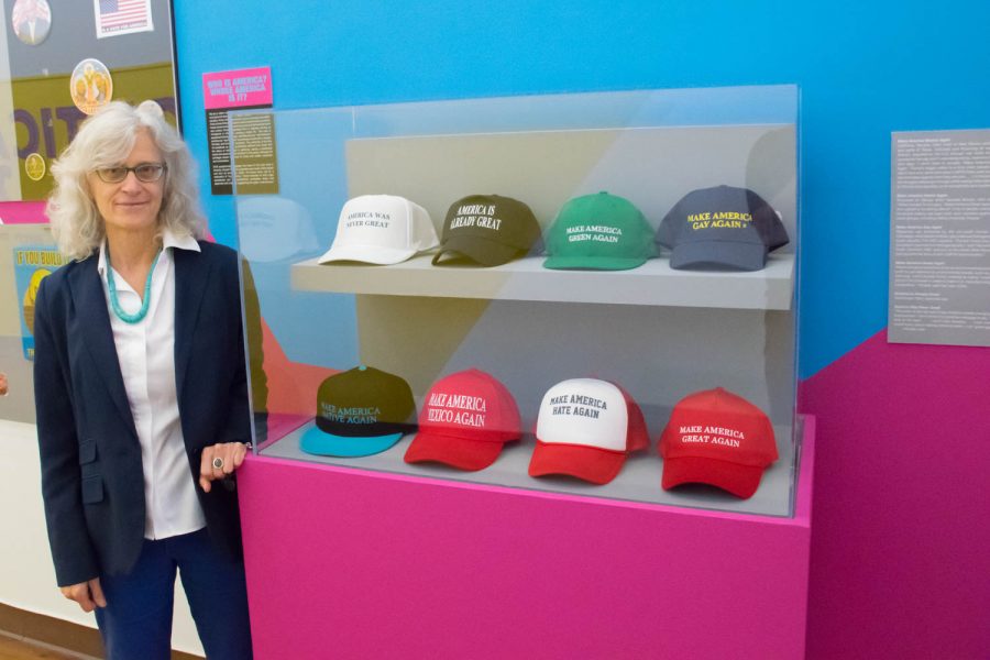 FAU’s Gender and Women’s Studies Professor and “Political Slideshow 2016” curator/creator Jane Caputi Poses for a photo with her favorite piece from the election exhibit.  Craig Ries | Contributing Photographer
