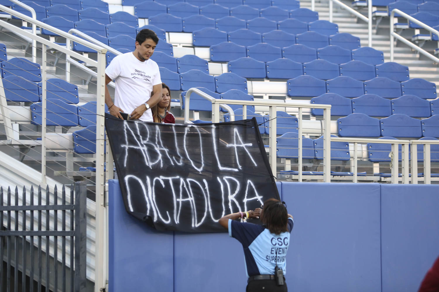 A sign that reads Down with dictatorship in Spanish is removed by an event supervisor during the match between Venezuela and Ecuador. Photo by Alexander Rodriguez