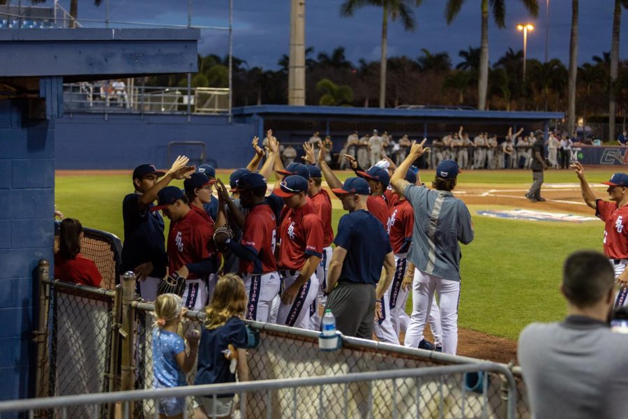 Photo of the FAU Baseball team celebrating by the dugout on March 2, 2022.
