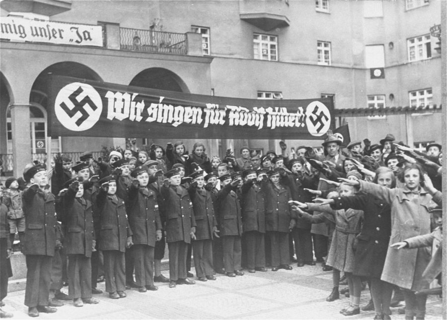 The Vienna Boys Choir, assembled under a banner that reads, We sing for Adolf Hitler! salute Adolf Hitler and his entourage during his first official visit to Vienna after the Anschluss. Dated March 13, 1938. Courtesy of the U.S Holocaust Memorial Museum.