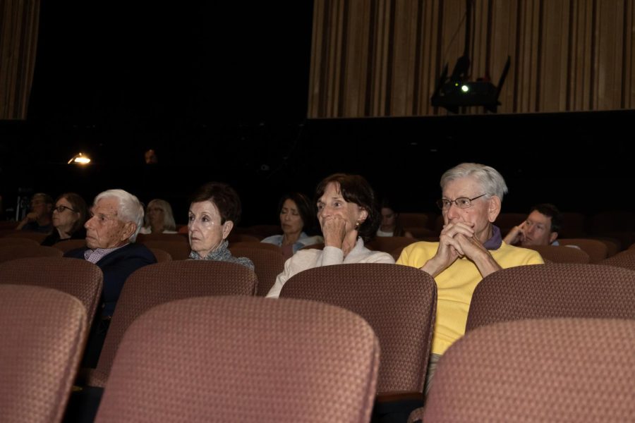 Audience members watching videos of the stories of Holocaust survivors.