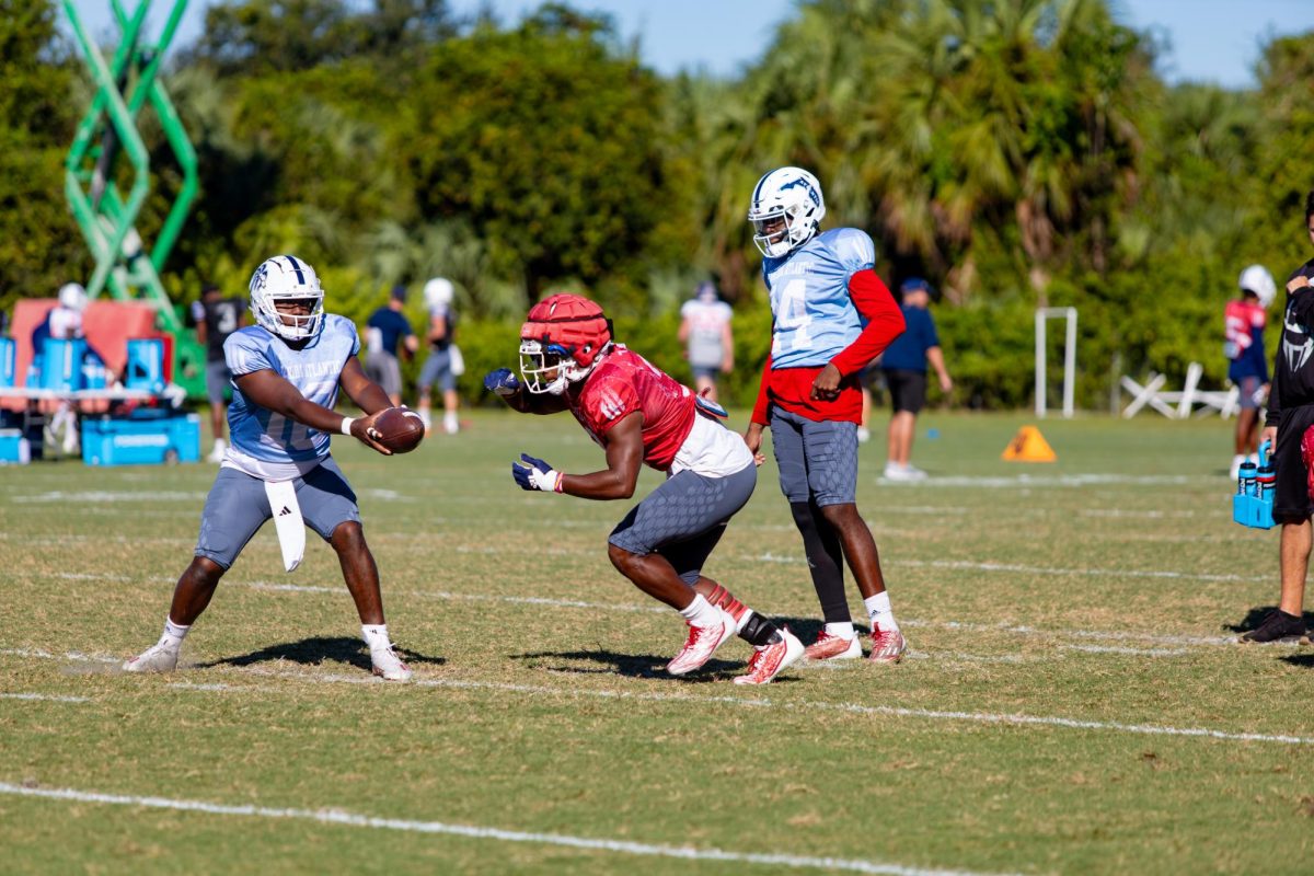 FAU senior running back Larry McCammon III gets ready to receive a handoff from junior quarterback Daniel Richardson (10) during early morning practice on Tuesday, Oct.17, 2023 at FAU’s Practice Facility. 