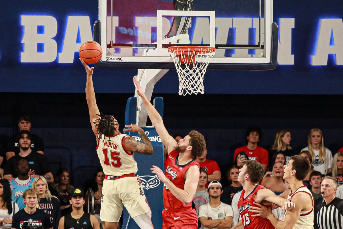 FAU junior guard Alijah Martin (#15) going up for a layup against Liberty redshirt junior forward Shiloh Robinson (#33) during the Owls 83-58 victory on Thursday, Nov. 30, 2023.