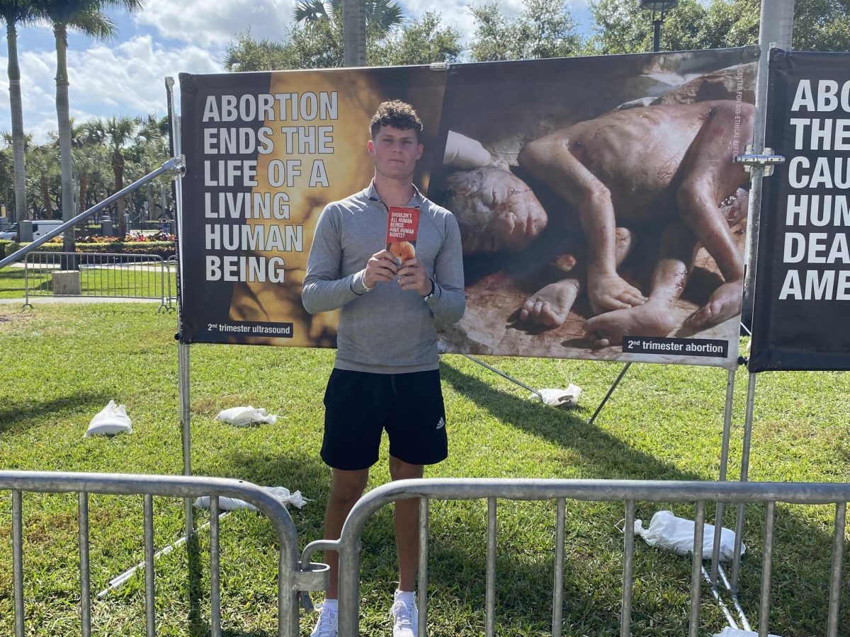 A pro-life activist from the Canadian Centre for Bio-Ethical Reform holding their pamphlet in front of the College of Social Work and Criminal Justice building on the Boca campus, Wednesday, Feb. 28, 2024.