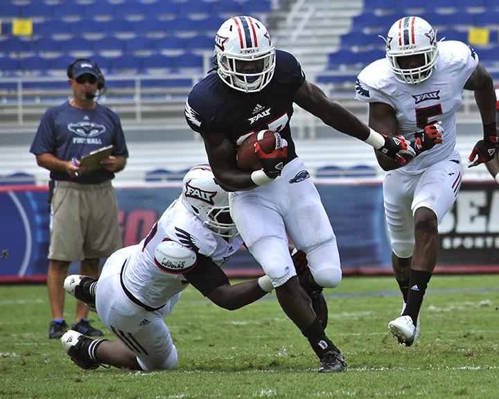 Senior Runningback Jonathan Wallace rushes the ball while Coach Carl Pelini watches in the spring football game on April 20, 2013. Photo by Melissa Landolfa